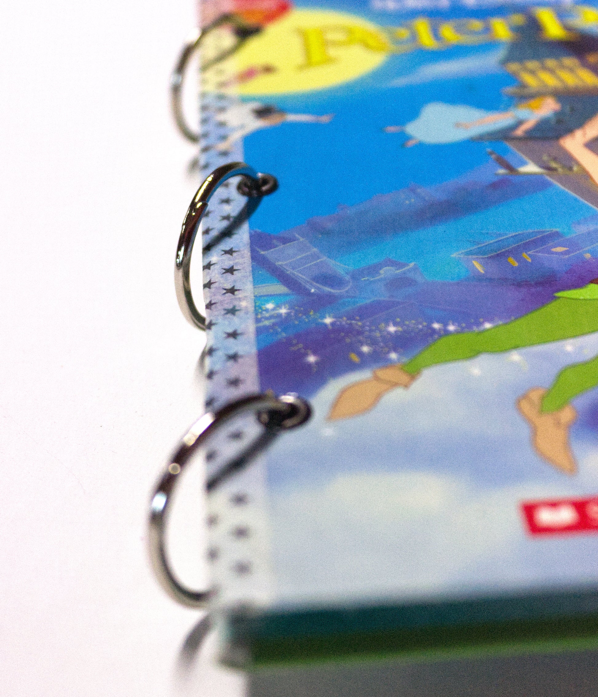 Side view of an upcycled Peter Pan journal showing layered pages and ring binding.