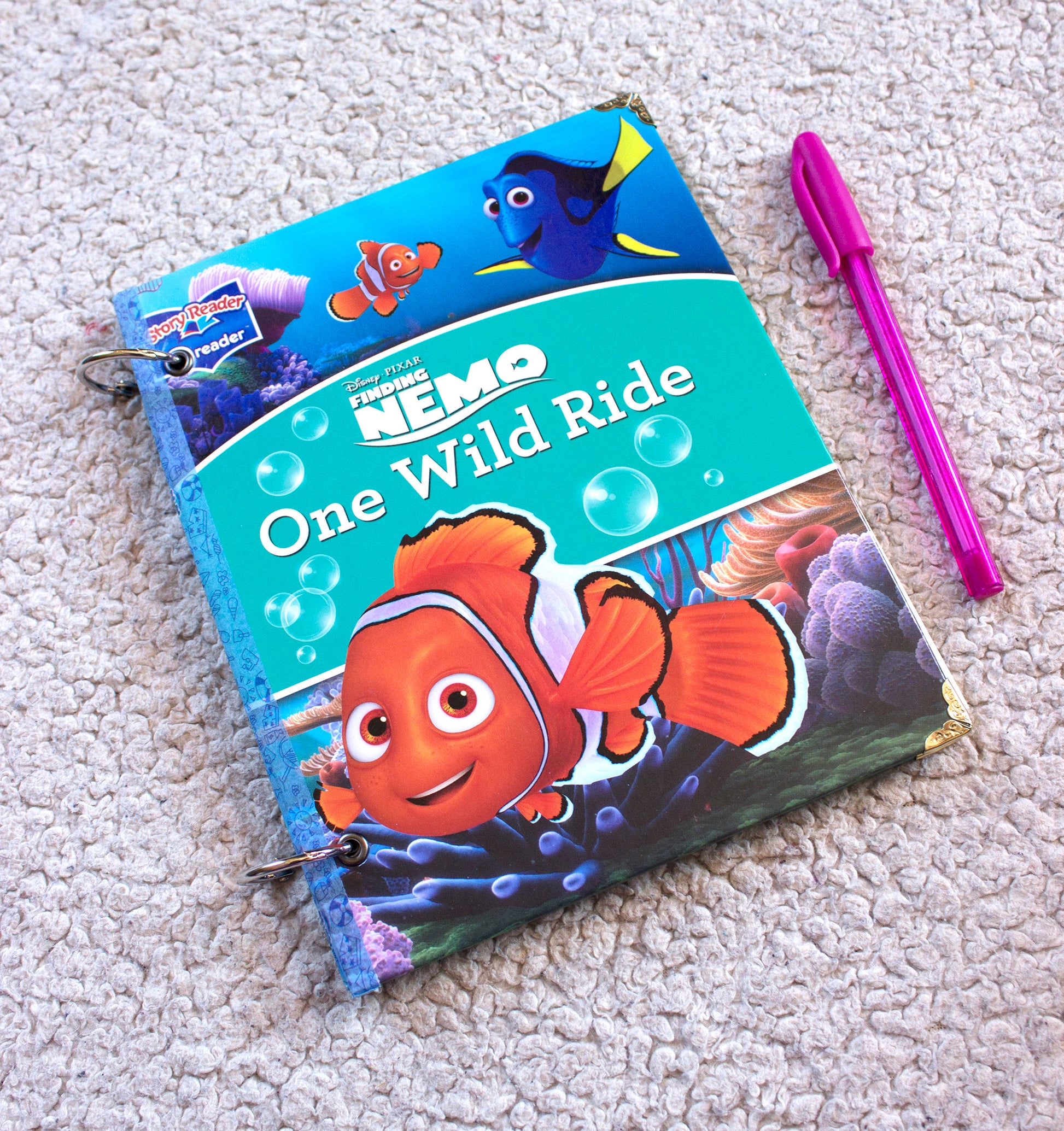 Upcycled children’s book journal made from a Finding Nemo hardcover, featuring a colorful ocean scene with animated fish characters, metal ring binding, and reinforced corners.